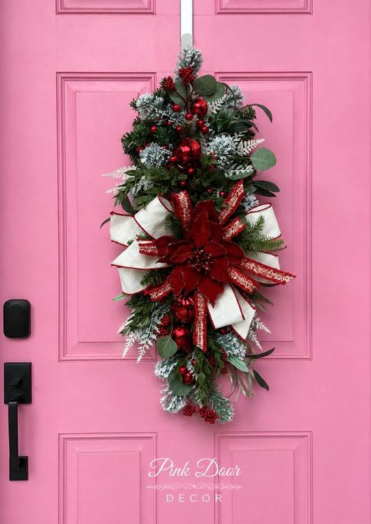 Christmas teardrop swag with red velvet poinsettia and ornaments on the pink door