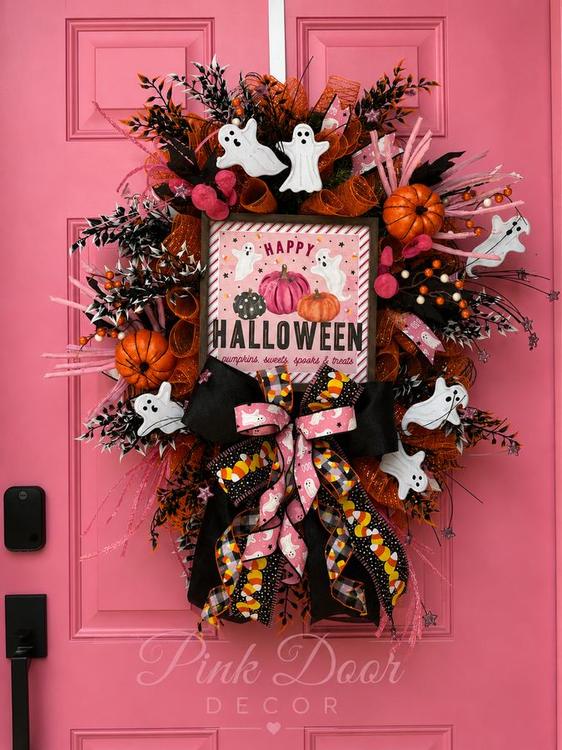 Pink and orange Happy Halloween wreath with ghosts, pumpkins, and candy corn ribbon on the pink door