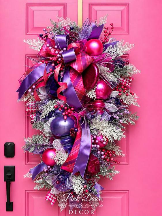 Pink and purple Christmas swag with plaid bows, satin ribbon, and magenta ornaments on the pink door