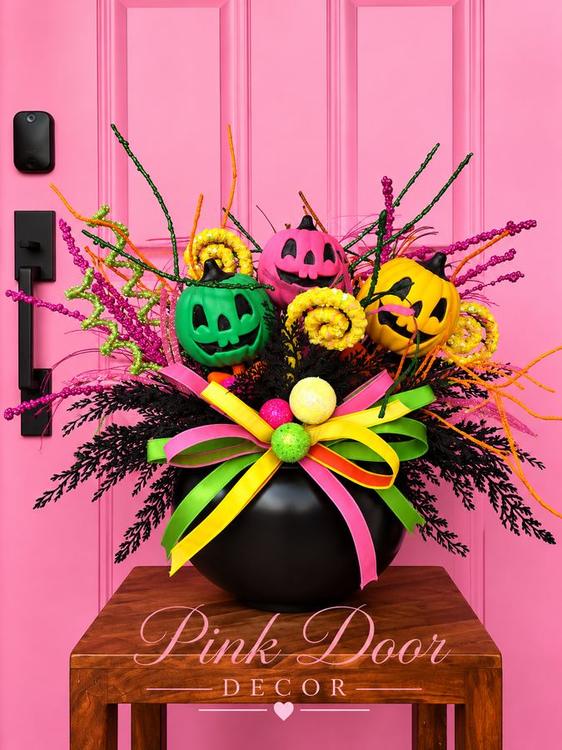 Black cauldron centerpiece with neon green, pink, and gold jack-o-lanterns