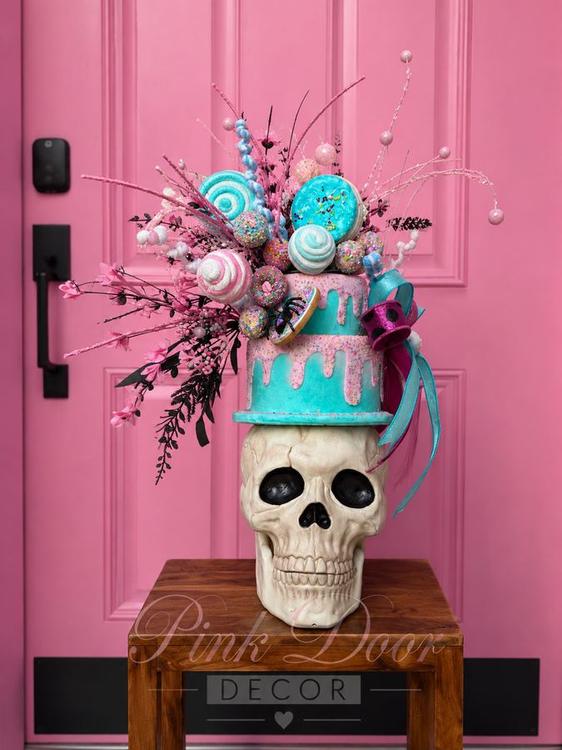 Skull centerpiece with two-tier pastel drip cake and lollipop sprays