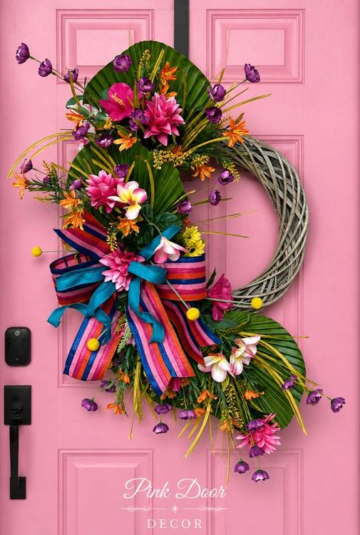 Tropical willow wreath with palm fans, plumeria, and a striped bow on the pink door
